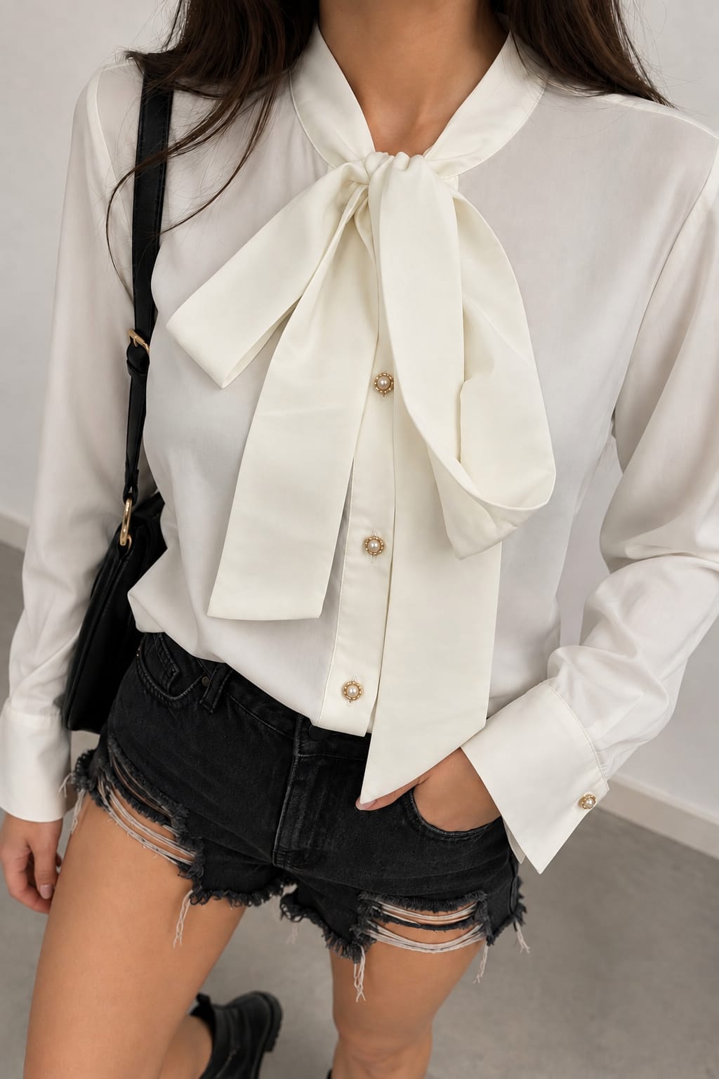 Blouse styled with a shoulder bag and black denim shorts