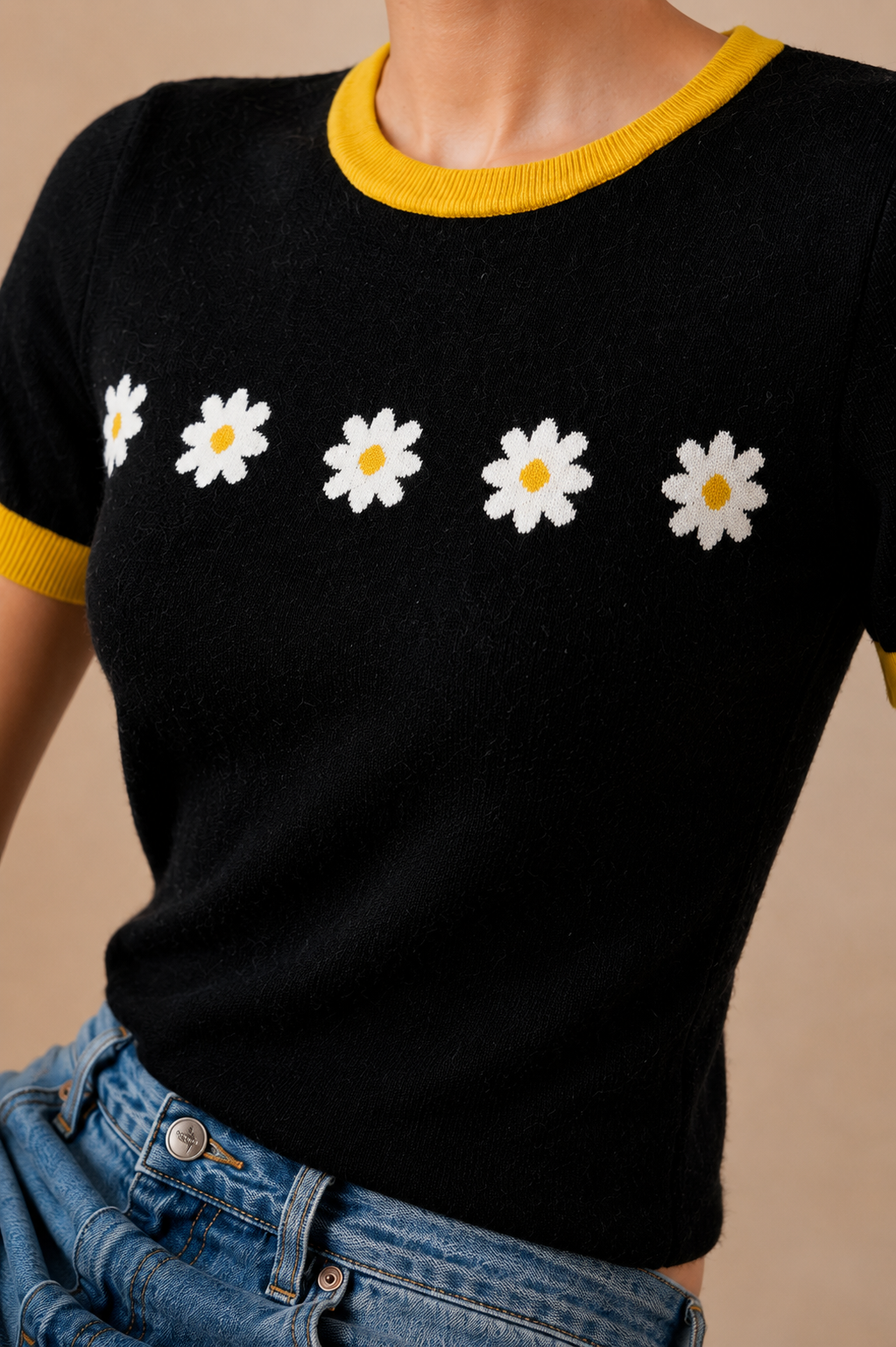 Close detail of white daisy motif and marigold ribbed neckline
